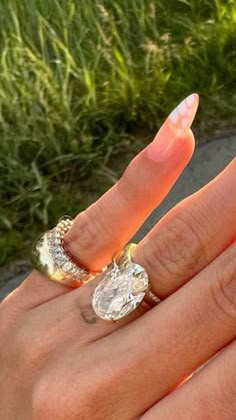 a woman's hand with two rings on it and an oval shaped diamond in the middle