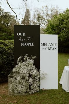 two black and white signs sitting next to each other on top of a lush green field