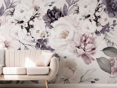 a white couch sitting next to a wall covered in flowers