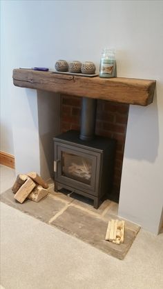 a wood burning stove in a living room next to a pile of firewood on the floor