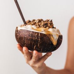 a woman holding up a coconut drink in her hand