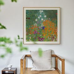 a painting hanging on the wall next to a chair and vase with flowers in it