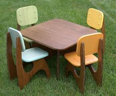 three children's wooden chairs sitting at a table in the middle of some grass