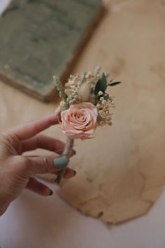 a person holding a flower in their hand on top of a piece of parchment paper