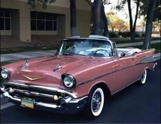 an old pink car parked in front of a building