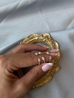 a woman's hand with pink and white manicures holding onto a gold plate