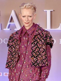 a woman with blonde hair wearing a purple shirt and black pants on the catwalk