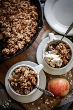 two bowls filled with granola next to an apple