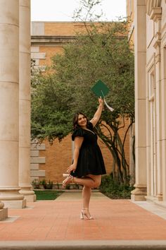 a woman in a black dress holding up a green frisbee while standing on a brick walkway