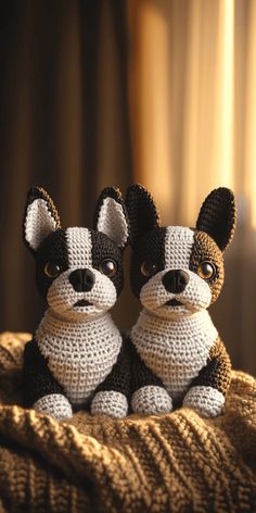 two small crocheted dogs sitting on top of a bed next to each other