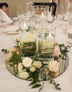 flowers and candles are arranged on a round glass plate at the center of a table