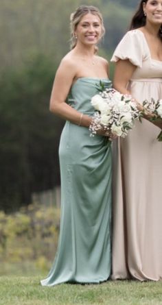 two women standing next to each other holding bouquets