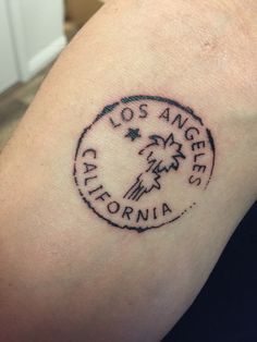 a person with a tattoo on their arm that says los angeles, california and palm trees