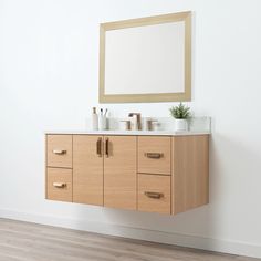 a bathroom vanity with two sinks and a mirror on the wall above it in a white room