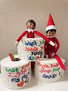 two elfs are sitting on top of toilet paper