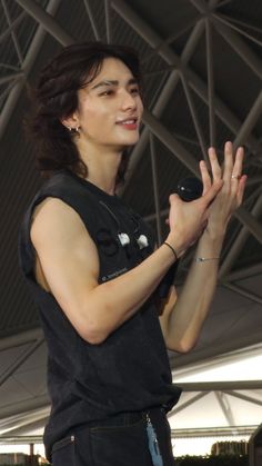 a woman standing in front of a microphone and holding her hands up to the side