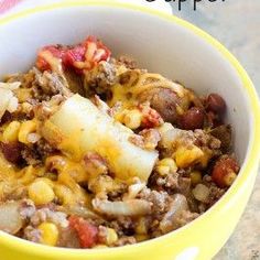 a yellow bowl filled with food sitting on top of a table next to a red and white towel