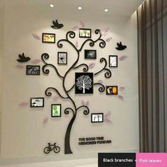 a tree with many pictures on it and birds flying around the tree, in front of a white wall