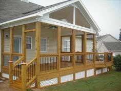 a porch with wooden railings next to a house