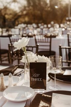 there is a table set with white flowers and place settings