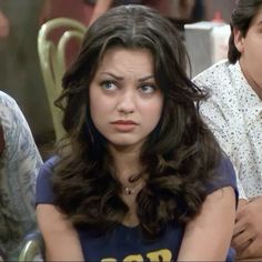 a woman sitting next to a man at a table in front of him and another person behind her