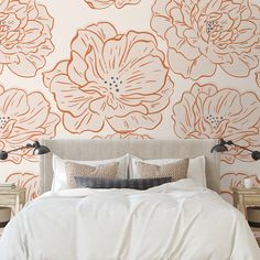 a bed with white linens and orange flowers on the wall