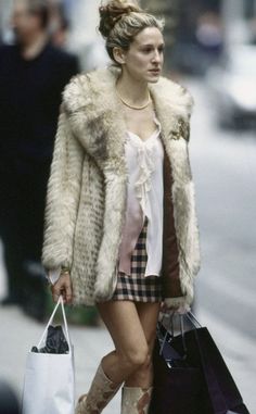 a woman is walking down the street with shopping bags in her hand and wearing boots