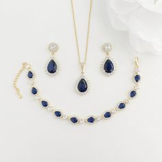 "Gorgeous blue and gold bridal jewelry set of earrings, necklace and bracelet with sapphire blue and clear cubic zirconia stones. The earrings are in the classic teardrop style with halo set round ear posts. Comes with a matching necklace and bracelet. Material used is 14k gold plated brass and the ear posts are hypoallergenic stainless steel pins, nickel free. Also available in rhodium/silver finish and rose gold finish.  Ideal for bride for 'something blue' or for mother of groom or bride. - l Blue Sapphire Jewelry Set, Sapphire Jewelry Set, Blue Bridal Earrings, Blue Jewelry Set, Blue Sapphire Jewelry, Blue Pendant Necklace, Backdrops Necklace, Bracelet Rose Gold, Gold Bridal Jewellery Sets