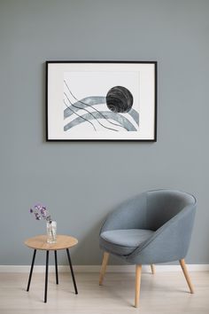 a chair and table in front of a gray wall with a painting on the wall