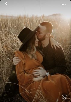 a couple cuddles in the tall grass as the sun shines on them