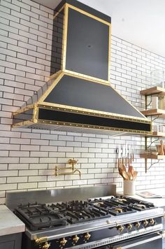 a black and gold stove top oven in a kitchen with white bricks on the wall