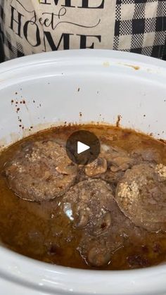 a white crock pot filled with meatballs and gravy on top of a table