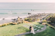 a bride and groom walking down the aisle to their wedding ceremony on the beach in front of the ocean