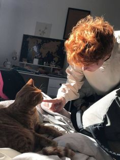 a woman petting a cat on top of a bed