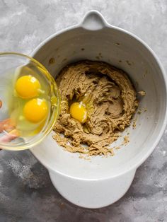 two eggs are being mixed in a bowl with some brown stuff on the counter top