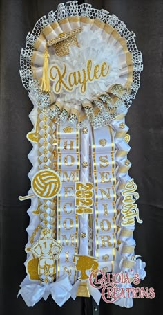 a graduation decoration with gold and white ribbons