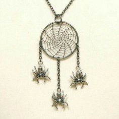 two spider webs attached to a chain with silver colored beads and chains hanging from it