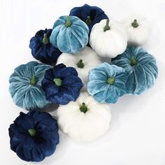 blue and white pumpkins are arranged on a white surface