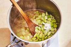 a pot filled with green vegetables and a wooden spoon