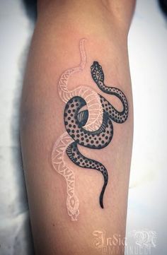 a black and white snake tattoo on the arm