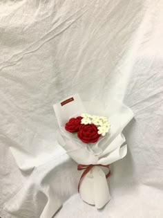 a red and white flower bouquet on a white sheet