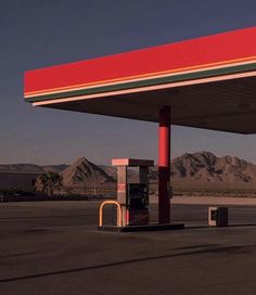 an empty gas station with mountains in the background