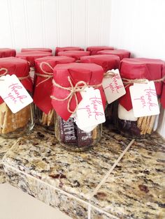 several jars filled with different types of food on top of a granite counter topped with red and white tags