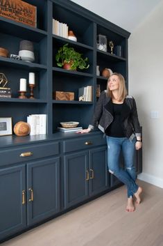 a woman standing in front of a blue bookcase