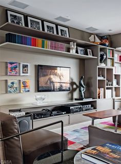 a living room filled with furniture and a flat screen tv mounted on a wall next to a book shelf