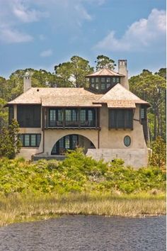 a large house sitting on top of a lush green field next to a body of water