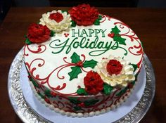 a decorated christmas cake with holly and red flowers on it, sitting on a silver platter