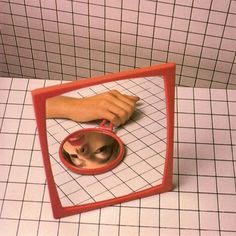 a person's hand is reflected in a mirror on the floor with a small dog