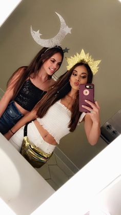 two beautiful young women standing next to each other taking a selfie in front of a mirror