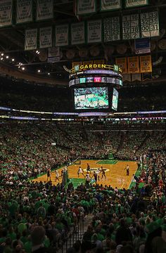 a basketball game is being played in a large arena with people sitting on the sidelines